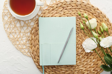 Beautiful composition with notebook, cup of tea and flowers on white background