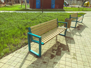 wooden benches in the park. a place for recreation for city residents, unity with nature. outdoor time near greenery and water. next to a trash bin made of wood and a playground