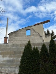 A wall of a house with space for window. The house is being built or rebuilt. Behind it there is blue sky. Low angle view. 