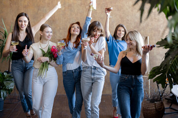 Young girlfriends having fun together, walking with flowers and drinks. Celebrating women's day or having hen-arty. Concept of female friendship and beauty. Women with different hair color wearing