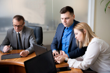 Roundtable meeting of business partners. Business people talking and using laptops and tablets.