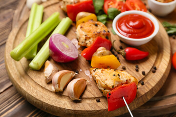Board of grilled chicken skewer with vegetables and sauce on table, closeup