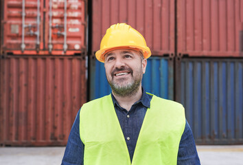 Professional dock worker wearing hardhat and safety vest standing at container yard port of import and export