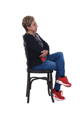 side view of a full portrait of serious woman  sitting on chair on white background