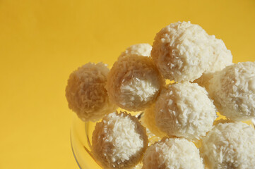 coconut balls. delicious candies with coconut chips. sweet dessert on a yellow background.