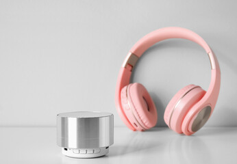 Wireless portable speaker and headphones on light background