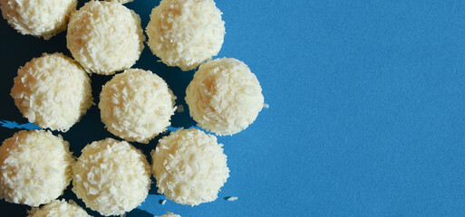coconut balls. delicious candies with coconut chips. sweet dessert on a blue background.