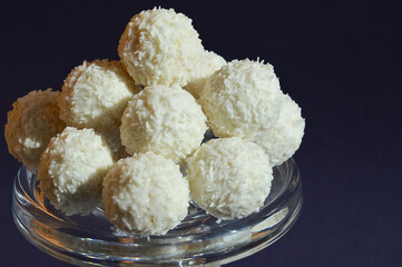 coconut balls. delicious candies with coconut chips. sweet dessert on a dark blue background.
