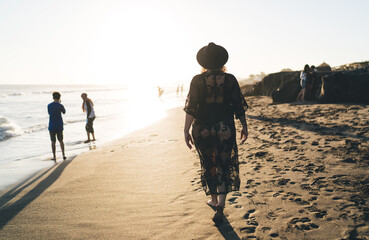 Young traveller enjoying getaway journey trip for recreating on Mauritius island spending summertime at sandy tropical beach, back view of female tourist in black swimwear have seashore promenade © BullRun