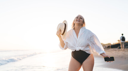 Cheerful plus size woman feeling happiness during summer vacations visiting seashore and tropical...