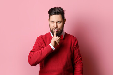 Fototapeta premium Stylish bearded man showing silence gesture on pink background