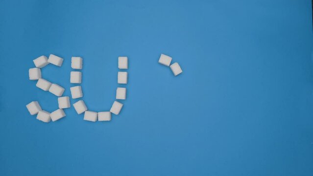 Stop motion animation. The word sugar gradually appears and disappears from the cubes of white sugar on a blue background. The word is collected from sugar. Shooting from the top point.