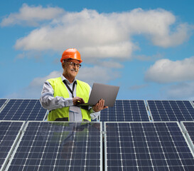 Mature male engineer using a laptop computer on a solar panel station