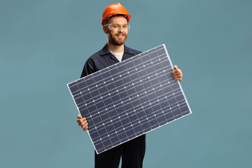 Young male worker in a unifrom holding a solar cell photovoltaic module