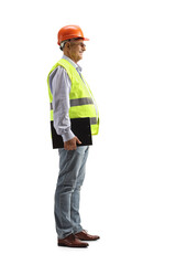 Full length profile shot of a mature male engineer with a safety vest and hardhat holding a clipboard