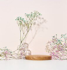 stage for displaying products, cosmetics with a round wooden podium and a glass vase with a bouquet...