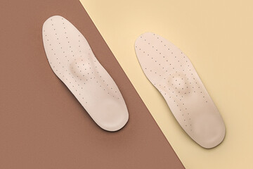 Pair of orthopedic insoles on color background