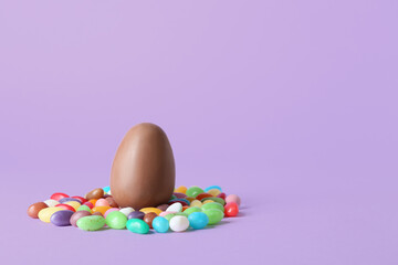 Fototapeta na wymiar Chocolate Easter egg and candies on purple background