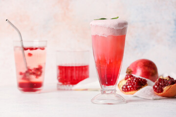Glasses of tasty pomegranate cocktail on light background