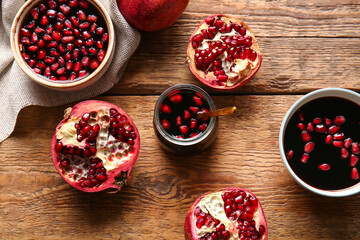 Jar and bowls of pomegranate molasses with fresh fruits on wooden background
