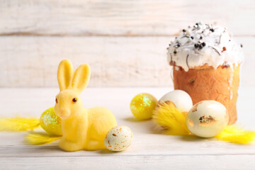 Cute Easter bunny with cake and painted eggs on light background