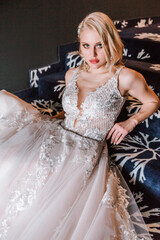 An attractive pensive blonde woman with a creative hairstyle for short hair is sitting on a steps in hotel.