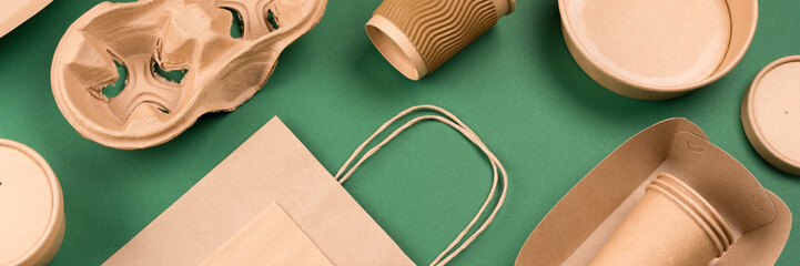 Banner with eco-friendly tableware - kraft paper utensils on green background. Paper cups and...