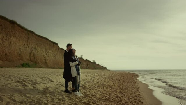 Couple cuddling beach sea on holiday. Happy mixed race lovers hug at ocean shore