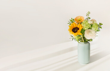 Bouquet with  flowers in a vase on table against the background of a white wall. Minimalistic scandinavian mockup with copy space.