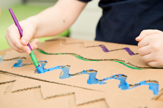 Zero waste. Corrugated cardboard cut and glued to make terrain. boy painting it to look like sea. DIY games at home. save the ocean concept.
