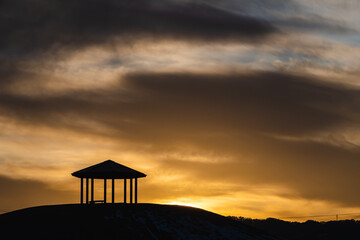 夕日にうかぶ丘の上のあずま屋