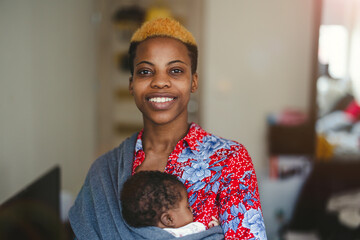 Mother with newborn in baby sling carrier at home
