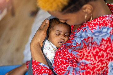 Mother cuddling sleeping baby at home
