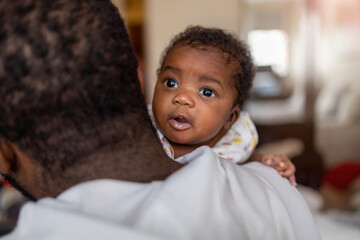 Father holding his baby in arms at home
