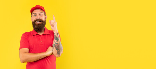 Happy deliveryman in casual red cap and tshirt keeping finger raised copy space, idea