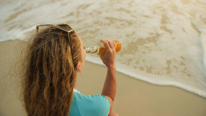 View top woman in swimwear on the beach drinks alcohol. Parting love, divorce from husband, bad...