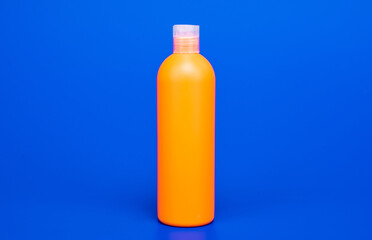 orange shampoo bottle on blue background, cosmetology