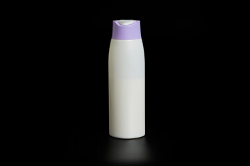 Unbranded bottle of shampoo, cream rinse, cream or beauty product with purple cap on black background with reflection below.