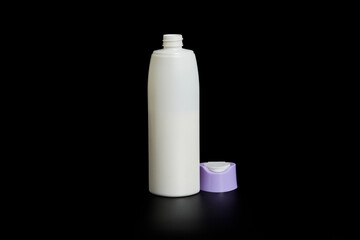 Unbranded bottle of shampoo, cream rinse, cream or beauty product with purple cap on black background with reflection below.