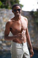 Grabbing a cold one. A young man smiling at the camera while holding a beer.