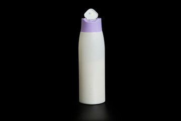 Unbranded bottle of shampoo, cream rinse, cream or beauty product with purple cap on black background with reflection below.