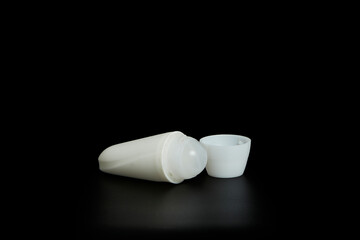 Unmarked bottle of deodorant on black background with reflection below.