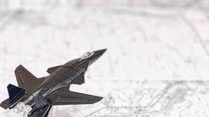 A black toy combat aircraft flies over a map
