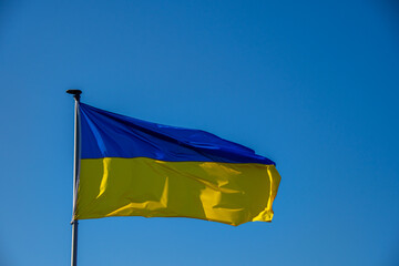 A Ukraine flag against a cloudless sky