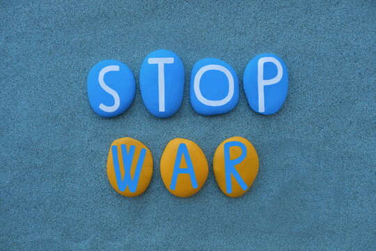 Stop War, conceptual slogan composed with hand painted ukrainian national colors painted on stones over green sand
