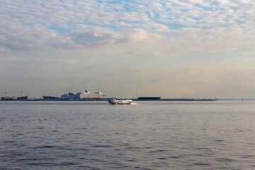 a high-speed hydrofoil sails against the backdrop of cruise ships in the Baltic Sea