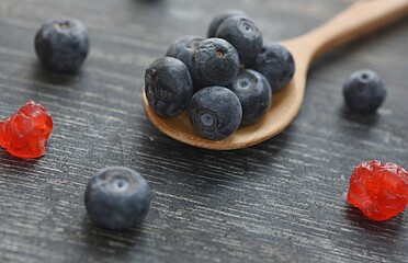 blue blueberries on a wooden spoon close-up on a dark wooden background