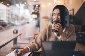 Young millennial asian girl working in cafe