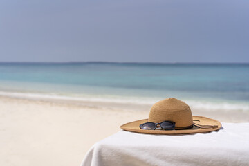 Fototapeta na wymiar Straw hat on a sunbed on a background of white sand and sea of the Maldivian beach
