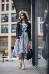 beautiful young woman in a hat and leather jacket near the mall. purchases. shopping